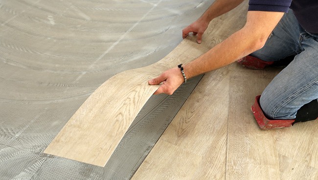 worker installing new vinyl tile floor | Mills Floor Covering